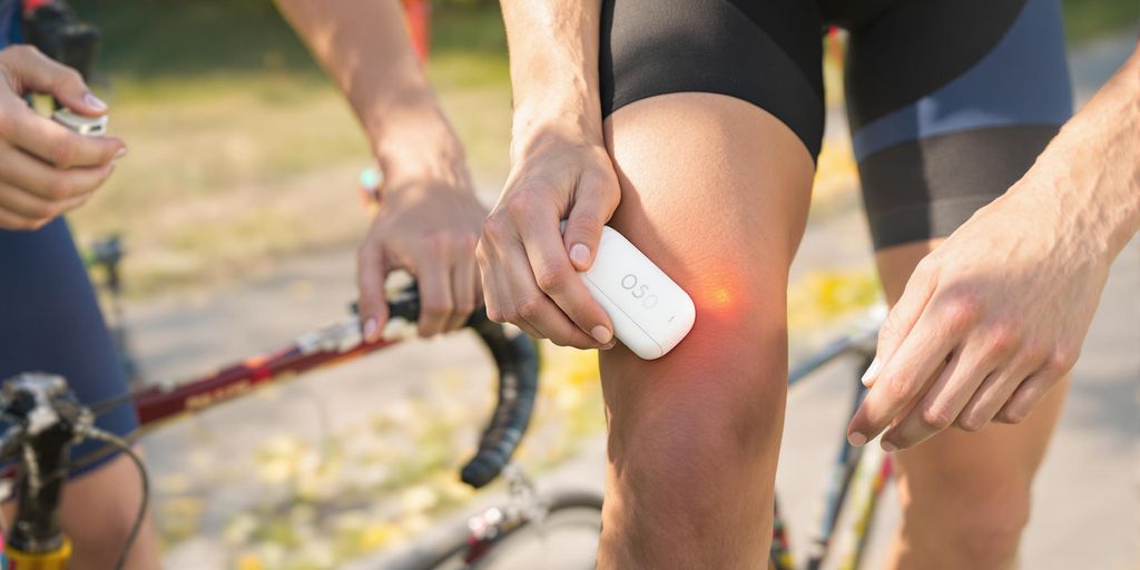 Runner using handheld laser device on smooth legs beside cycle.