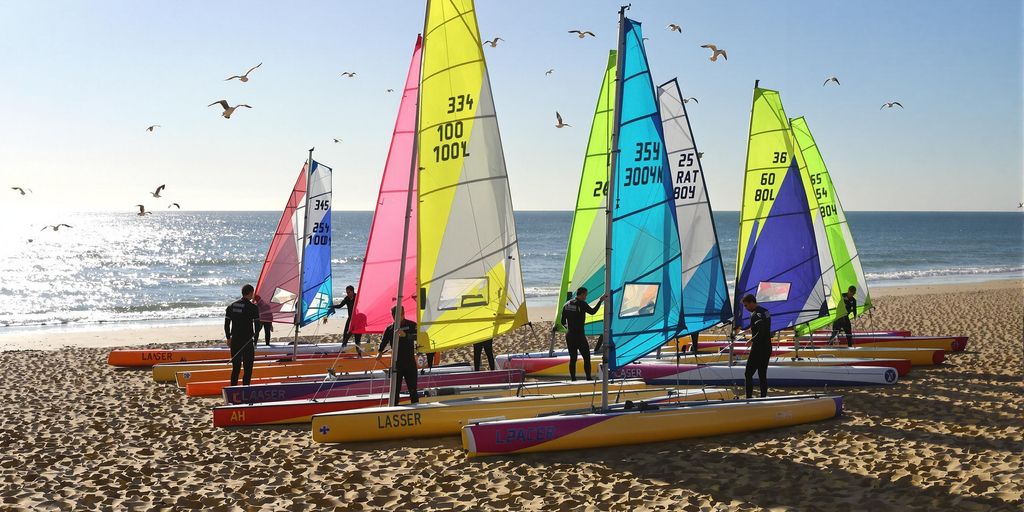 Laser sailboats lined up on Weston-super-Mare beach at quiet sunrise.