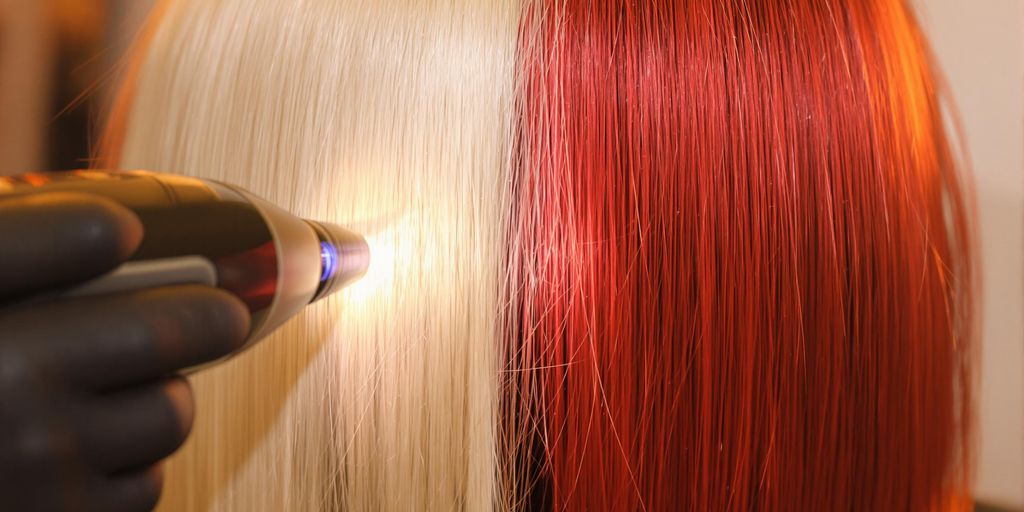 Salon technician applying diode laser to blonde and red hair