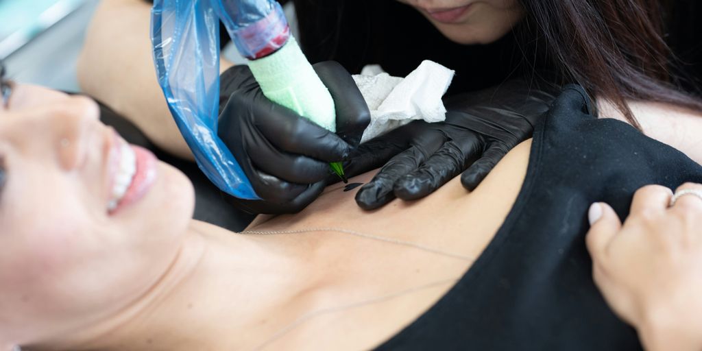 a woman getting a tattoo done by a tattooist