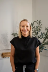 kim price at be laser and skin clinic stood in front of plain wall and plant